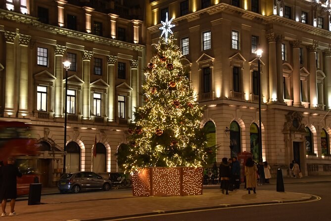 A Christmas tree lit outside a classical stone facade in the City of London at night