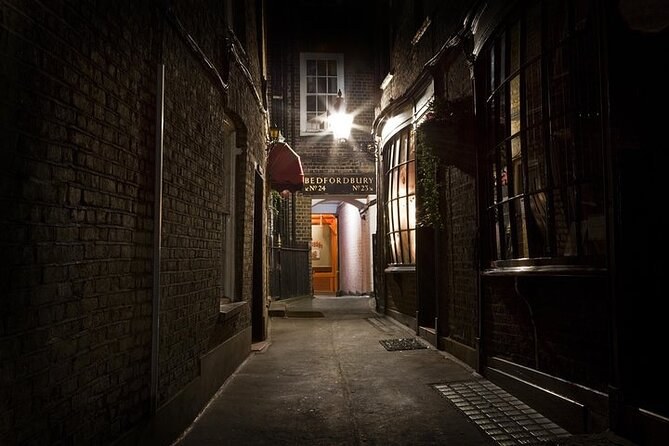 A narrow brick-walled alley in the East End at night, lit by a single lamp at the far end