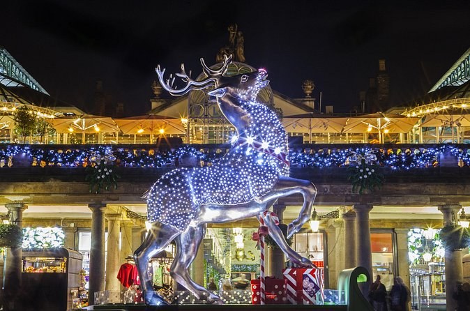 A reindeer sculpture picked out in white lights outside the Covent Garden market building at night