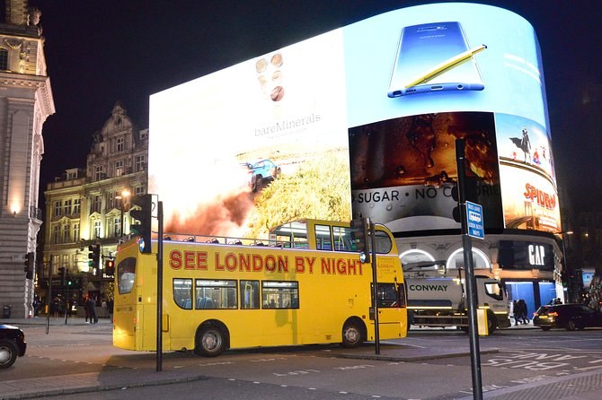 The advertising screens of Piccadilly Circus glowing at night above the traffic