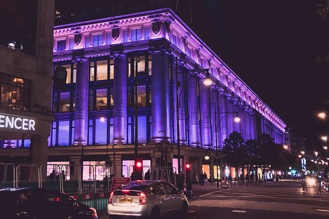 The Selfridges building on Oxford Street washed in purple light at night