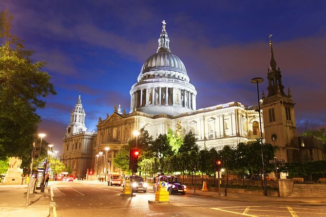 St Paul's Cathedral floodlit warm against a deep blue evening sky, with the traffic of Ludgate Hill below it