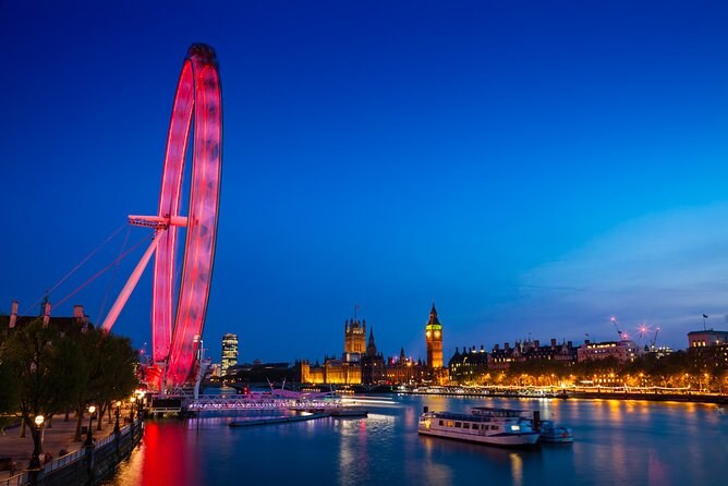The London Eye lit deep red at blue hour, with Big Ben and the South Bank reflected in the Thames beside it