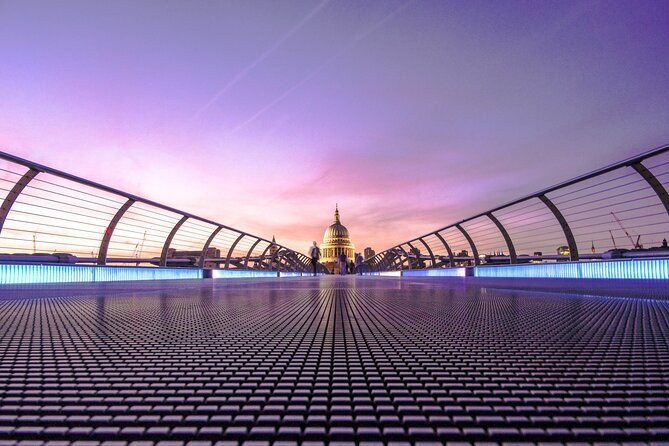 The empty deck of the Millennium Bridge leading to the dome of St Paul's Cathedral under a violet sky