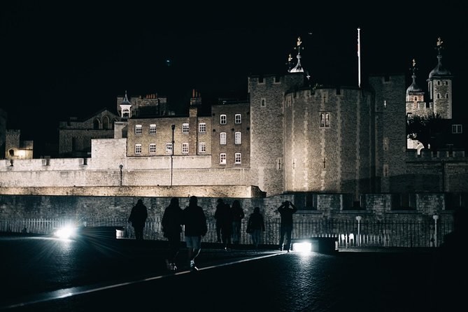 The White Tower and the outer walls of the Tower of London floodlit at night, seen across the empty moat