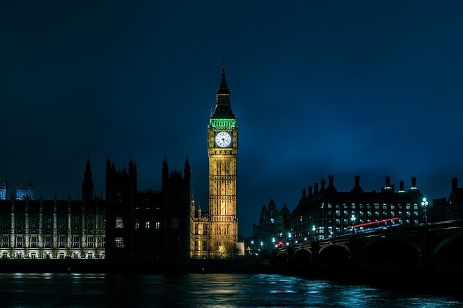 The Elizabeth Tower and Parliament at blue hour, lit against a deep indigo sky from the far bank of the Thames
